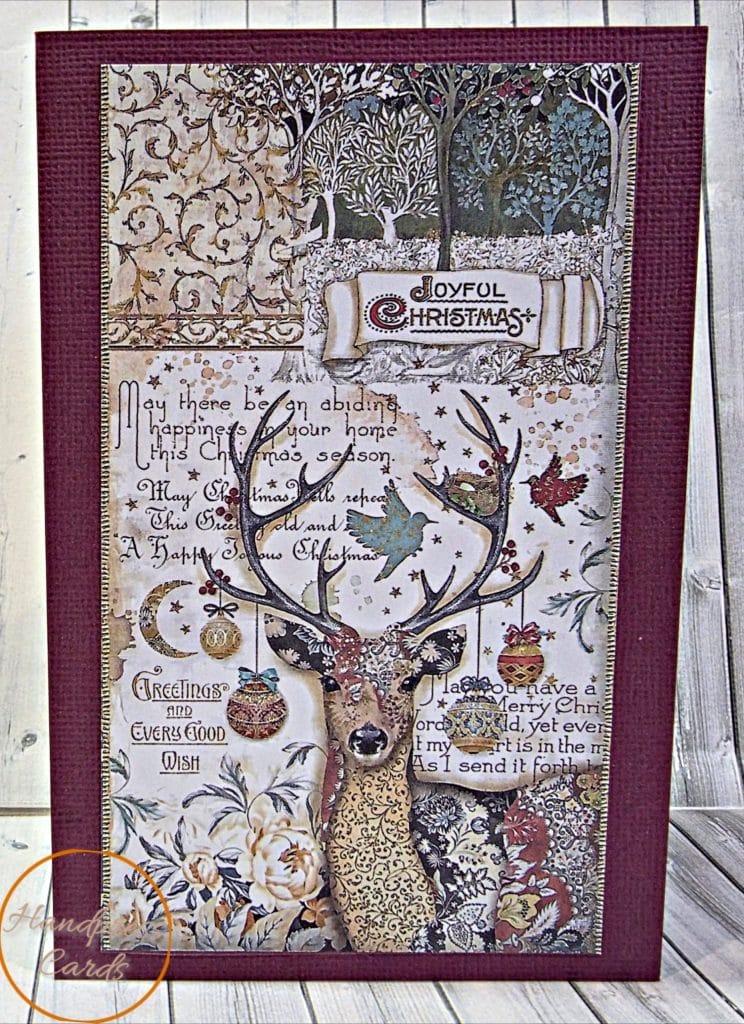 Handmade vintage Christmas card with a patterned stag, baubles, birds and a Joyful Christmas banner on a burgundy textured card